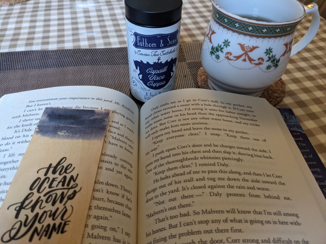 copy of The Scorpio Races by Maggie Stiefvater alongside bookmark, teacup and tea tin